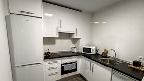 Eine moderne Küche mit weißen Schränken, einem Kühlschrank, einer Mikrowelle, einem Toaster und einem Geschirrspüler.