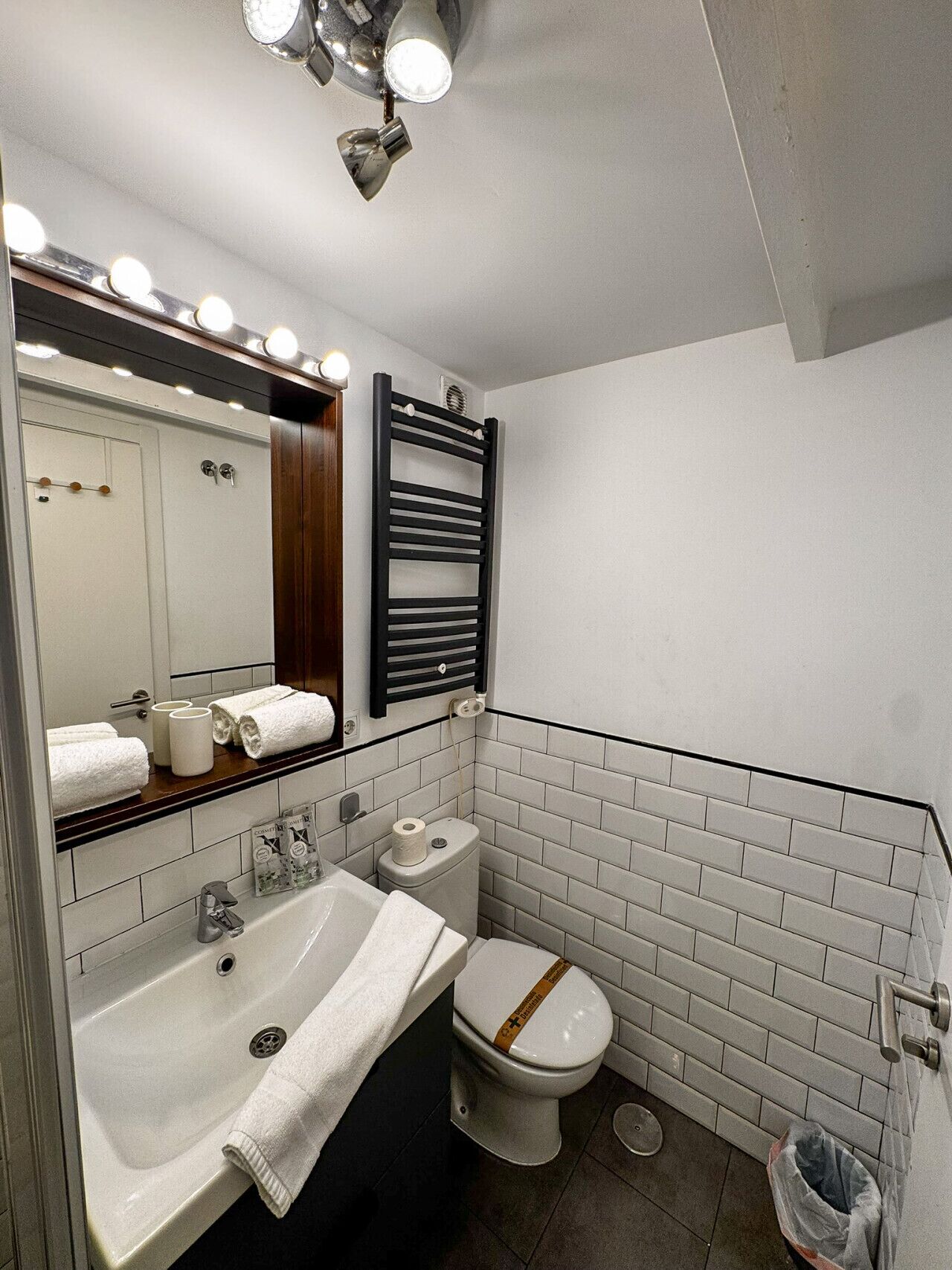 Un baño moderno con un lavamanos grande, un espejo y un perchero para toallas.