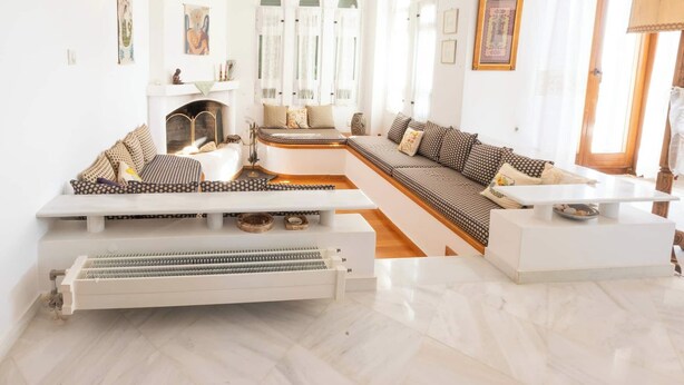 A modern living room with a fireplace, white walls, and a large sectional sofa. - Dual bay views by ΜΡS (Μαρίστρα)