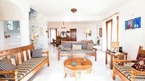 A spacious living room with a sofa set, a coffee table, and a dining area in the background. - Dual bay views by ΜΡS (Μαρίστρα)