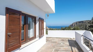A balcony with a view of the sea and a white building with wooden shutters. - Dual bay views by ΜΡS (Μαρίστρα)