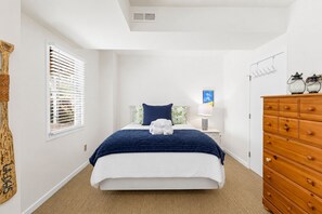 A bedroom with a bed, a dresser, a nightstand, a lamp, and a window with blinds. - 806 Carolina - 1 Block to Beach/Ocean! (Isle of Palms)