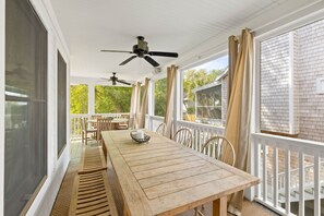 A covered patio with a wooden table, chairs, ceiling fans, and large windows. - 806 Carolina - 1 Block to Beach/Ocean! (Isle of Palms)