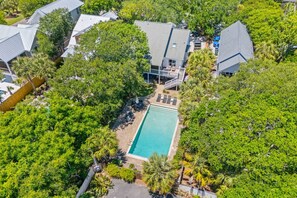 An aerial view of a residential area with a swimming pool surrounded by lush greenery and multiple houses. - 806 Carolina - 1 Block to Beach/Ocean! (Isle of Palms)