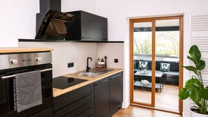 A modern kitchen with black cabinetry, a wooden countertop, and a built-in oven. - Vacation home in secluded location near Eifel National Park (Mechernich)