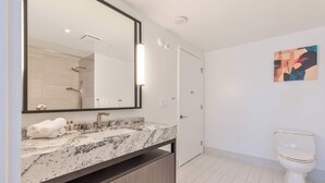 Un bagno moderno con un lavabo in marmo, uno specchio grande, un water e una doccia.