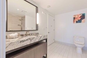 Ein modernes Badezimmer mit Marmorwaschbecken, einem großen Spiegel, Toilette und Dusche.
