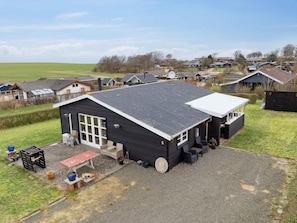 A black building with a large window and a covered outdoor seating area. - 4 Star Holiday Home in Roslev (Roslev)