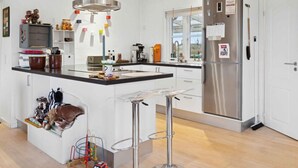 A modern kitchen with a stainless steel refrigerator, a central island with bar stools, and a variety of kitchen appliances and utensils. - 4 Star Holiday Home in Roslev (Roslev)