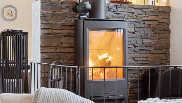 A stone wall, a black wood-burning stove, and a metal railing. - 4 Star Holiday Home in Roslev (Roslev)