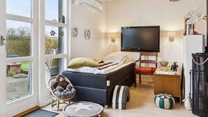 A bedroom with a bed, a television, a chair, and a window. - 4 Star Holiday Home in Roslev (Roslev)