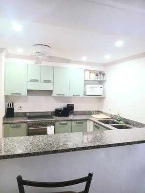 A kitchen with granite countertops, a stove, a microwave, and cabinets. - Breathe Easy at this Relaxing Beach Front Property (Christ Church)