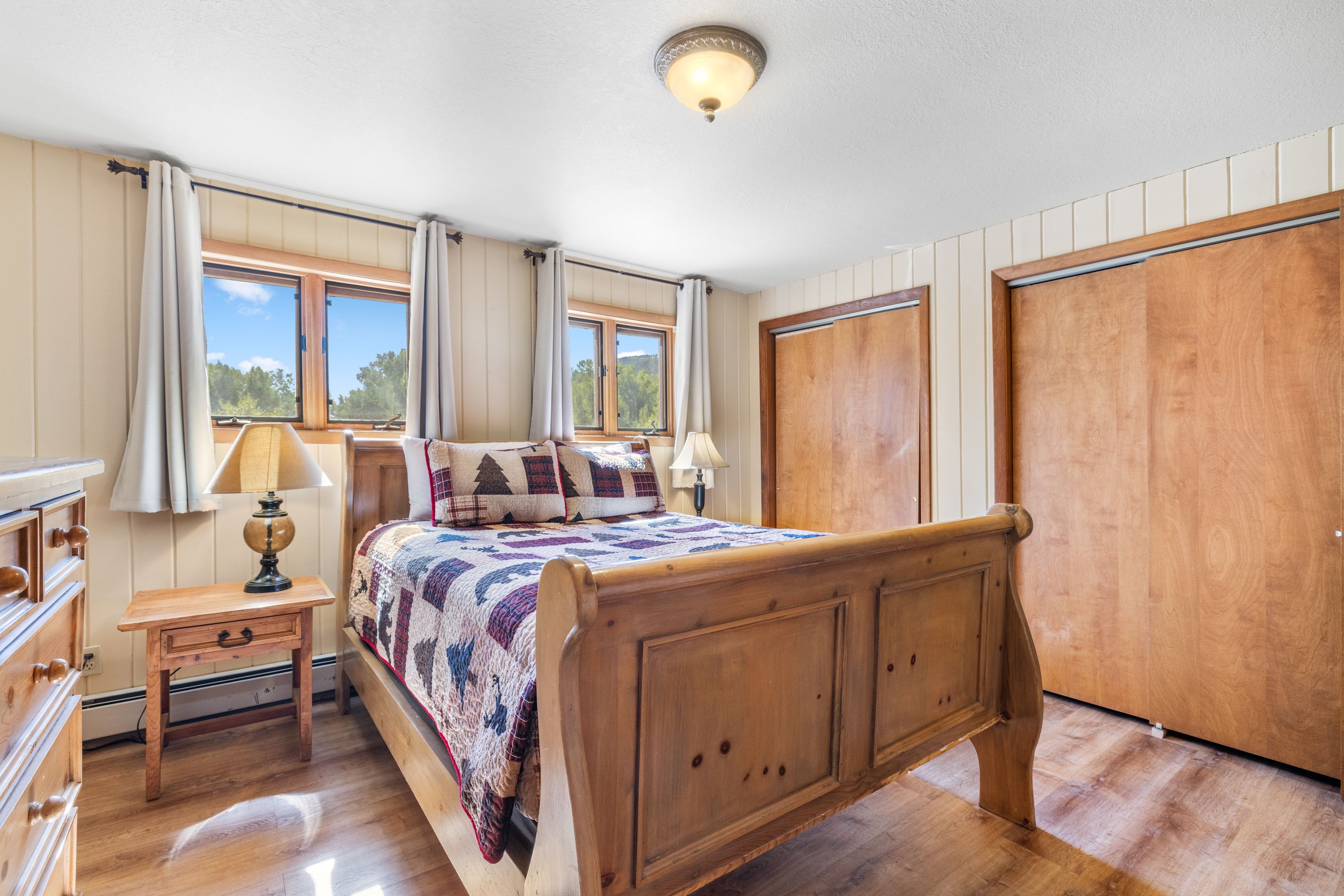 A bedroom with a wooden bed, a nightstand, a dresser, and a wardrobe.