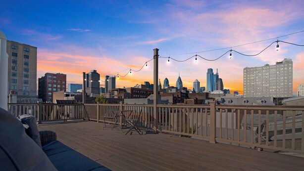 A rooftop deck with a view of a city skyline, outdoor seating, and string lights. - Rooftop Deck Chinatown Getaway w/Shared Gamroom (Philadelphia)