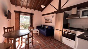 A compact kitchen with a dining table, chairs, a sofa, and a built-in stove.