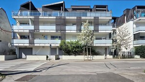 Un edificio residencial de varios pisos con balcones, una entrada portonada y un paso de peatones al frente.