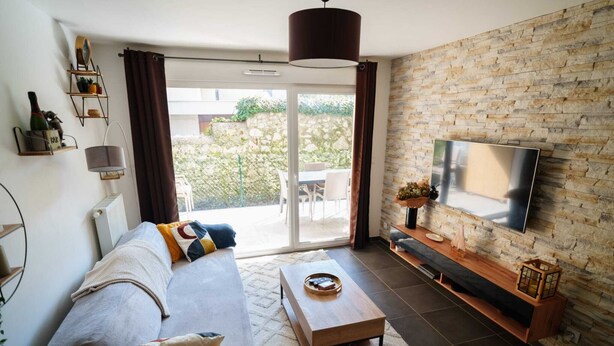 Una sala de estar moderna con un sofá, una mesa de centro, un televisor y una pared de piedra.