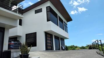 A modern two-story house with a car parked in the driveway and a potted plant in the foreground.
