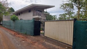 A two-story building with a balcony, a gated entrance, and a covered area. - Montezuma Jungle Room with Shared Bath, A/C and fast WiFi (Montezuma)