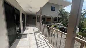 A balcony with a glass door, a ceiling fan, and a view of a parked car and greenery. - Montezuma Jungle Room with Shared Bath, A/C and fast WiFi (Montezuma)
