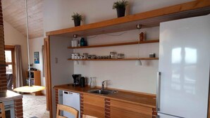A compact kitchen with wooden countertops, a built-in dishwasher, a refrigerator, and shelves above the counter. - 4 Star Holiday Home in Sjolund (Sjølund)