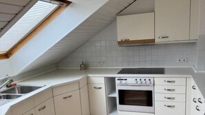 A kitchen with white cabinets, a wooden countertop, a skylight, and a built-in oven. - Haus Mechthild (Sindelfingen)