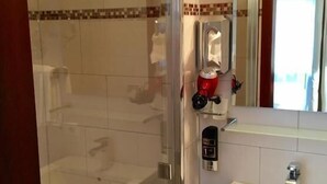 A bathroom with a glass-enclosed shower, a white sink, and a mirror. - Haus Mechthild (Sindelfingen)