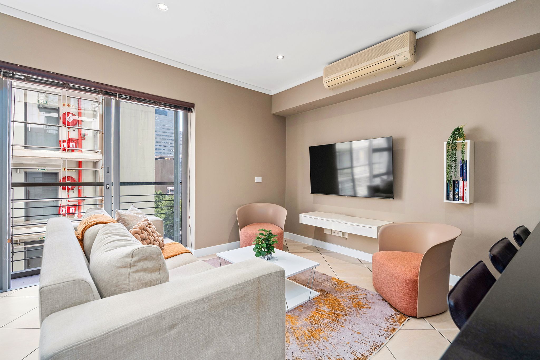 Ein modernes Wohnzimmer mit Sofa, Sesseln, Couchtisch, Fernseher und Bücherregal.