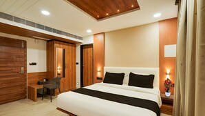 A bedroom with a large bed, a desk, a chair, and a wardrobe. - Deluxe Onyx Hotel (Bengaluru)