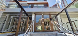 Der Eingang eines Hotels mit Glasfassade, Metallgeländern und einer sichtbaren Treppe zum Eingang.