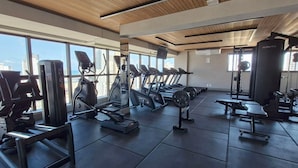 Ein Fitnessstudio mit Laufbändern, Krafttrainingsgeräten und Kurzhanteln.