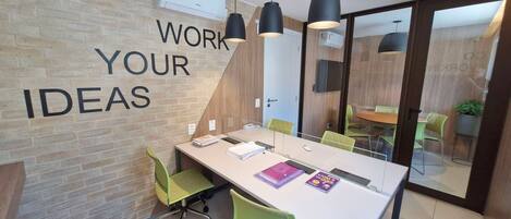 A modern office space with a long table, green chairs, and a wall with motivational text.