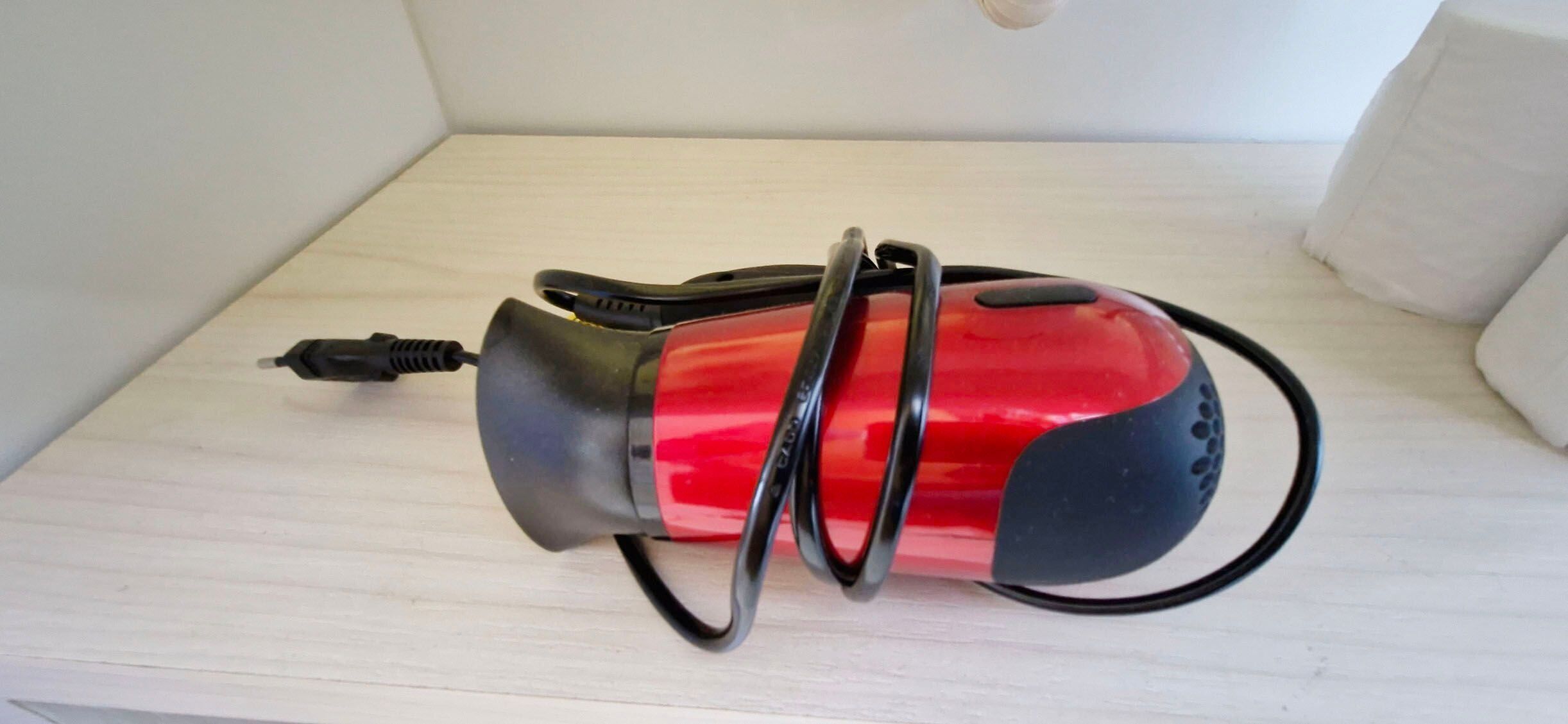 A red and black device with a cord on a wooden surface.