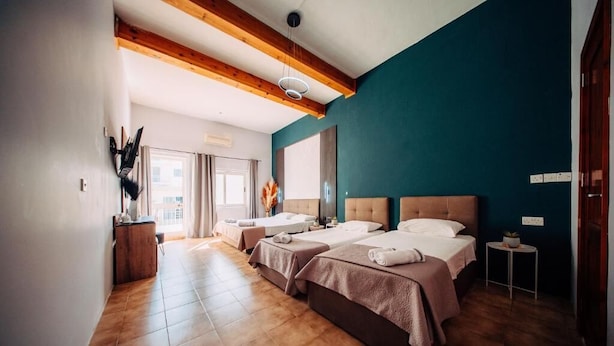 Una habitación de hotel con dos camas, techo de madera, un ventanal grande y una mesita auxiliar.