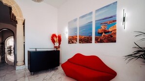 Un interior moderno con un sofá rojo, una consola negra y una pared con tres cuadros enmarcados.