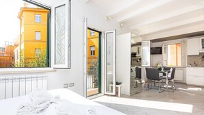 Ein modernes Hotelzimmer mit Bett, Blick auf die Stadt, Balkon und Küchenzeile.