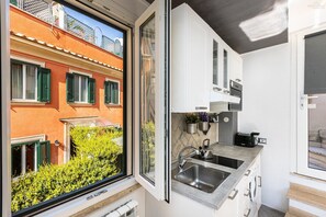 A compact kitchen with a window, a sink, and cabinets. - Monti Terrace Apartment with stunning views (Rome)