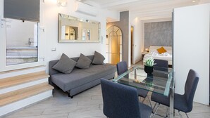 Ein modernes Wohnzimmer mit einem Glastisch, grauem Sofa und einem großen Spiegel.