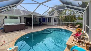 Une piscine couverte avec un jacuzzi, des chaises longues et un espace patio.