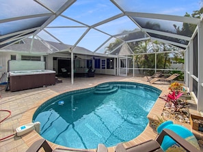 Ein überdachter Pool mit Whirlpool, Liegestühlen und einer Terrassenfläche.