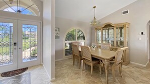 Uma sala de jantar com uma mesa grande, cadeiras e um candelabro.