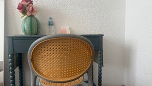 A chair with a woven backrest, a small table with a vase of flowers, and a bottle of water. - Cherry Blossom Boutique Hotel (Ho Chi Minh City)