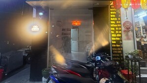 A storefront with a sign reading 'CHERRY BLOSSOM' and a list of services like haircuts and nail care. - Cherry Blossom Boutique Hotel (Ho Chi Minh City)