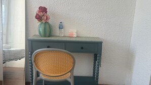 A room with a desk, chair, mirror, and a vase with flowers. - Cherry Blossom Boutique Hotel (Ho Chi Minh City)
