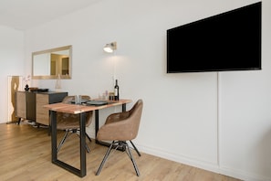 Ein modernes Zimmer mit Esstisch, Stühlen, einem Flachbildfernseher und einem Spiegel.