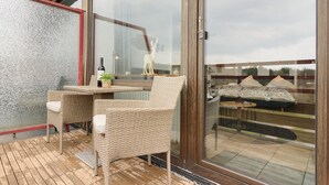 A balcony with wicker furniture, a glass door, and a view of the surrounding area. - Apartment 'Panoramablick Hahnenk' with Sea View, Wi-Fi and Air Conditioning (Goslar)