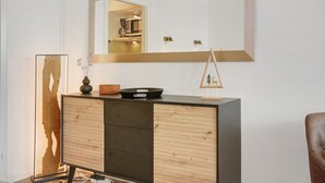 A modern room with a wooden cabinet, a mirror, and a small wooden sculpture. - Apartment 'Panoramablick Hahnenk' with Sea View, Wi-Fi and Air Conditioning (Goslar)