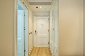Un pasillo con piso de madera, puertas blancas y un respiradero en el techo.