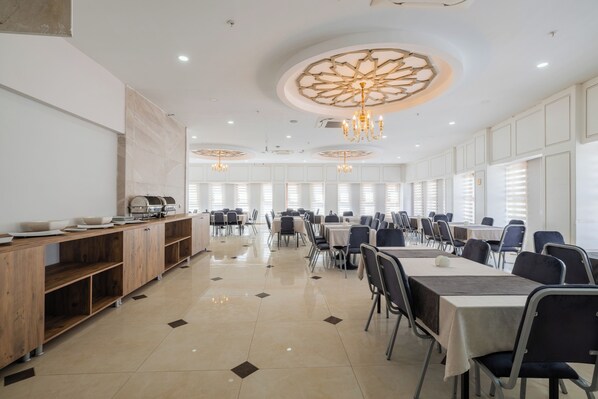 A spacious conference room with a long table, chairs, a buffet area, and decorative ceiling lights. - Minerva Hotel Kızkalesi (Erdemli)