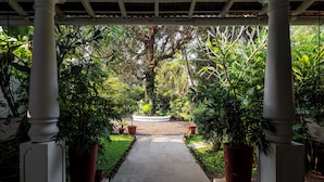A garden pathway with white columns, surrounded by lush greenery and potted plants. - Staymaster Villa Anasoh 4BHK (Vagator)